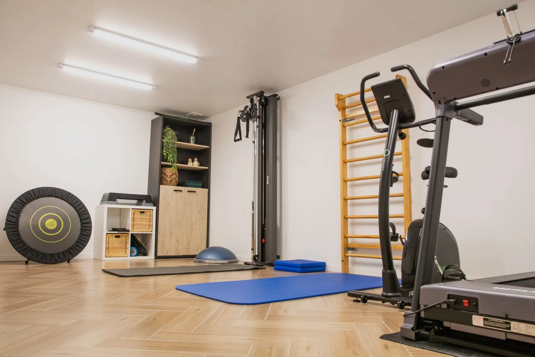 De oefenzaal met kabelstation, wandrek en cardiotoestellen